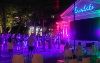 Couples dancing on an outdoor stage at the Silent Disco at Sandals Royal Barbados, enjoying a romantic and lively atmosphere under the night sky.